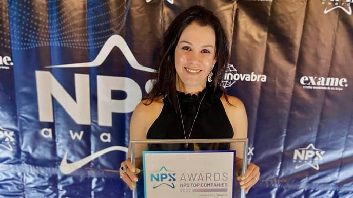 Liliane Siqueira na cerimônia de premiação do prêmio NPS Awards 2022. Na foto, ela segura a placa recebida pela Desktop.