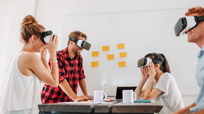 Quatro colegas de trabalho, sendo dois homens e duas mulheres, usando óculos VR.